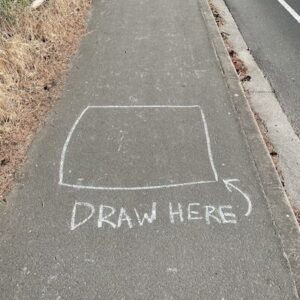 A white box drawn on the sidewalk with the words, "Draw here" next to it.